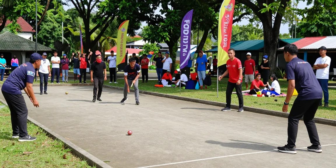 Pemain petanque di lapangan fopikotakendari.org dalam suasana bersahabat, dengan sorakan penonton di sekitar.