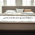 Showcasing the posturepedic logo on a luxury mattress in a beautifully decorated bedroom.