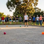 Aktivitas petanque di fopikotaparepare.org dengan atlet bersenang-senang di lapangan terbuka.